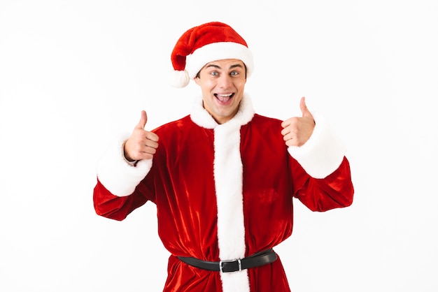 Retrato de homem otimista de 30 anos com fantasia de Papai Noel e chapéu vermelho gesticulando com um sorriso