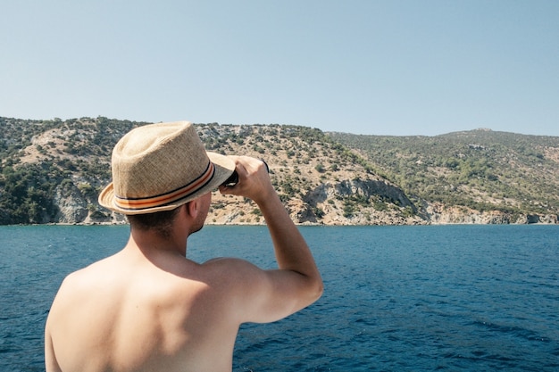 Retrato de homem parece através de binóculos. Conceito de turismo do mar. Bela paisagem natural na vista lateral de fundo