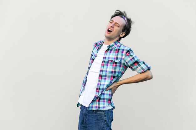 Foto retrato de homem que sofre de radiculite mantém a mão nas costas doloridas, estando doente e insalubre