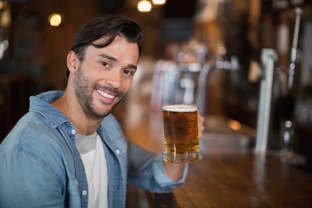 Retrato de homem segurando copo de cerveja no pub