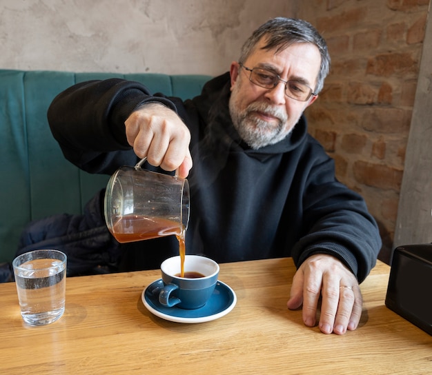 Retrato de homem sênior desfrutando de uma xícara de café alternativo no café