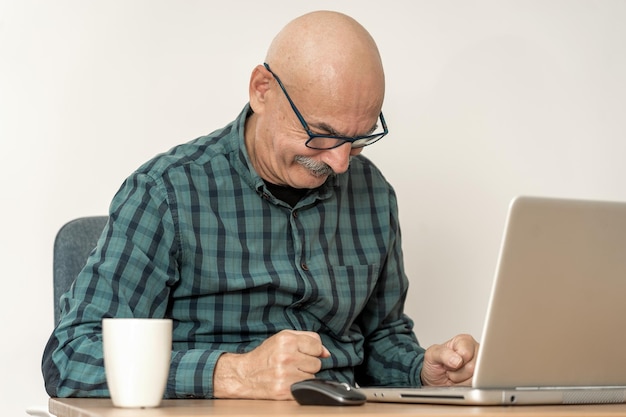 Retrato de homem sênior em casa trabalhando em um laptop