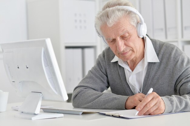 Retrato de homem sênior feliz trabalhando com computador