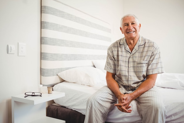 Retrato, de, homem sênior, sentar-se cama, e, sorrindo, em, quarto