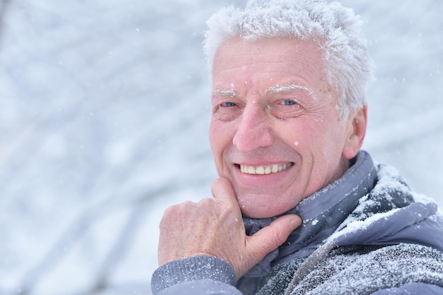 Retrato de homem sênior sorridente em pé ao ar livre no inverno