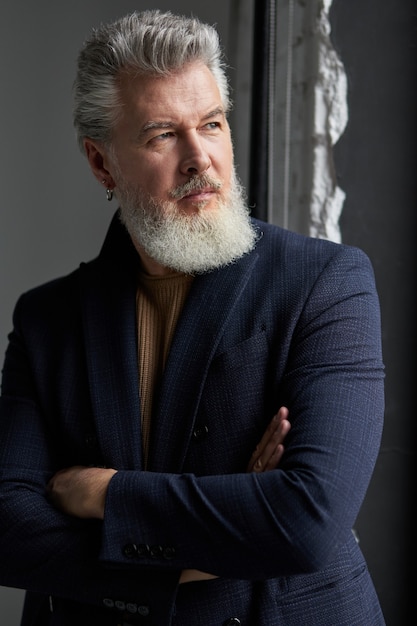 Retrato de homem sério de cabelos grisalhos, de meia-idade, em business casual wear, olhando para um