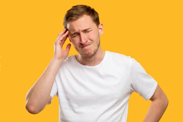 Retrato de homem sofrendo. Dor da enxaqueca. Estressado cara com forte dor de cabeça isolada em fundo laranja.