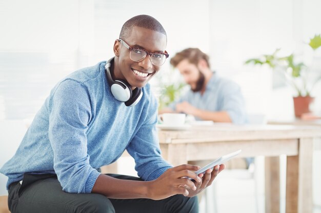 Retrato de homem sorridente com fones de ouvido enquanto usa um tablet digital