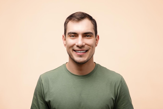 Retrato de homem sorridente em camiseta verde no espaço de cópia de modelo de maquete de fundo bege