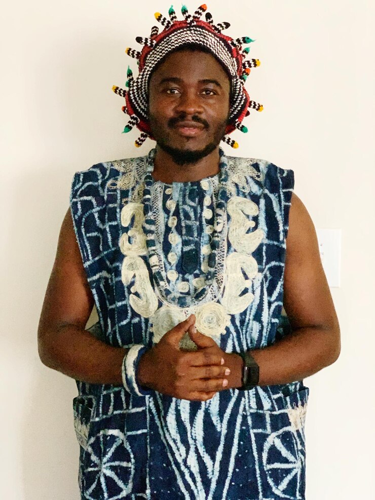 Foto retrato de homem sorridente em roupas tradicionais de pé contra fundo branco