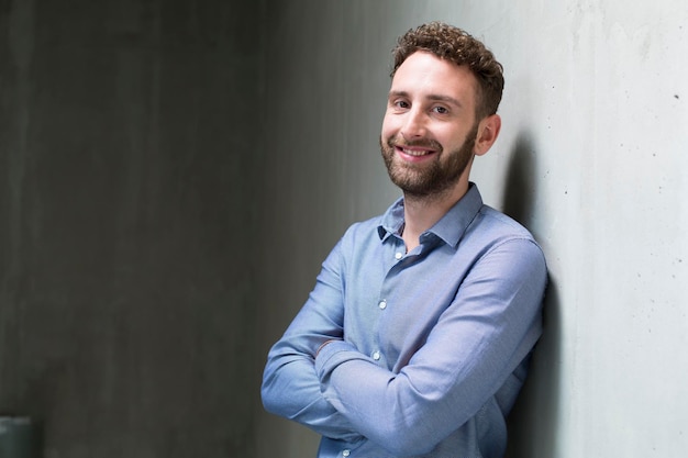 Retrato de homem sorridente encostado na parede de concreto