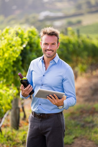 Retrato, de, homem sorridente, segurando, garrafa vinho, tablete