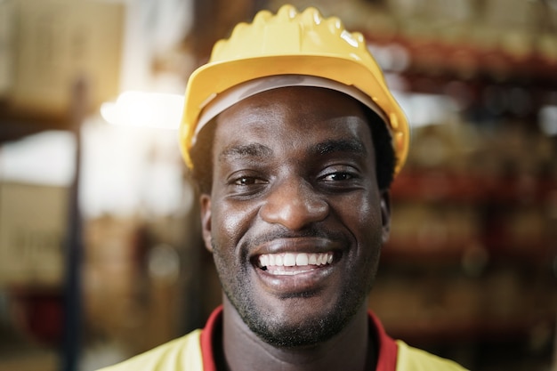 Retrato de homem trabalhador africano feliz olhando para a câmera dentro da loja - foco no rosto