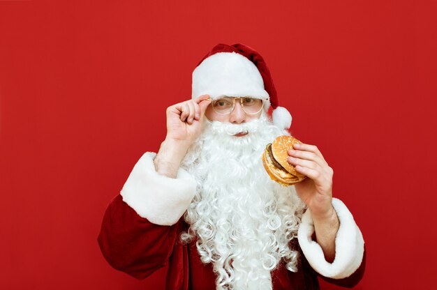 Retrato de homem vestido de Papai Noel segurando hambúrguer