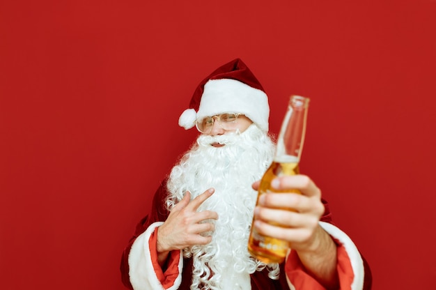 Retrato de homem vestido de Papai Noel segurando uma garrafa de cerveja