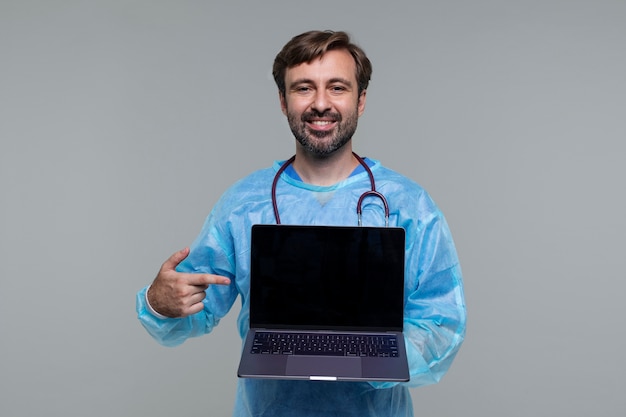 Retrato de homem vestindo bata médica e segurando laptop