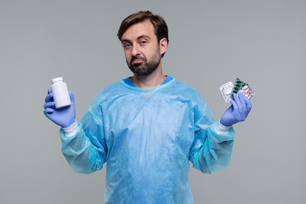 Retrato de homem vestindo bata médica e segurando pílulas