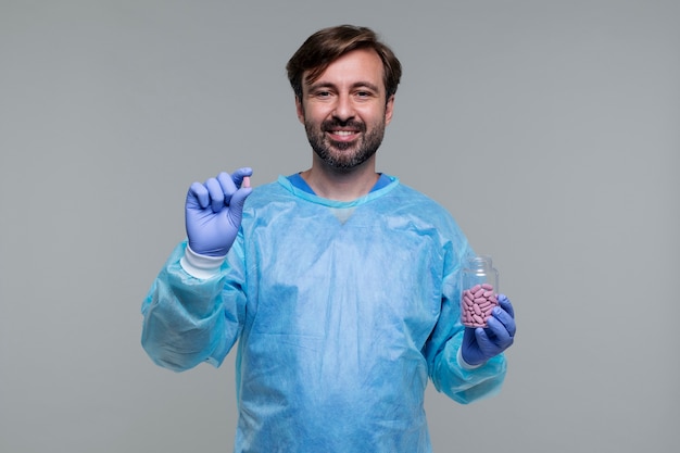 Foto retrato de homem vestindo bata médica e segurando pílulas