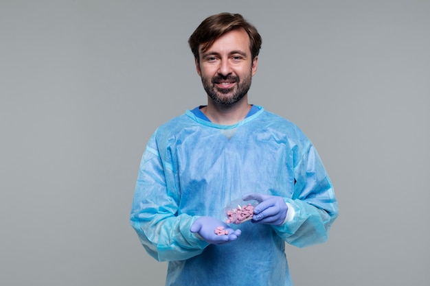 Retrato de homem vestindo bata médica e segurando pílulas