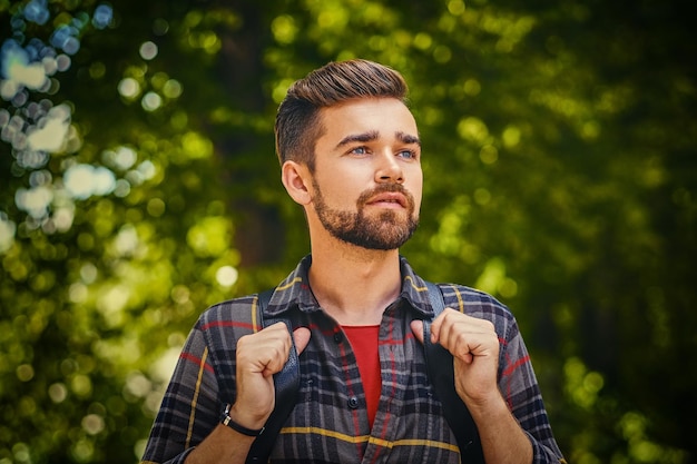 Retrato de homem viajante barbudo vestido com uma camisa de lã sobre fundo de parque selvagem.