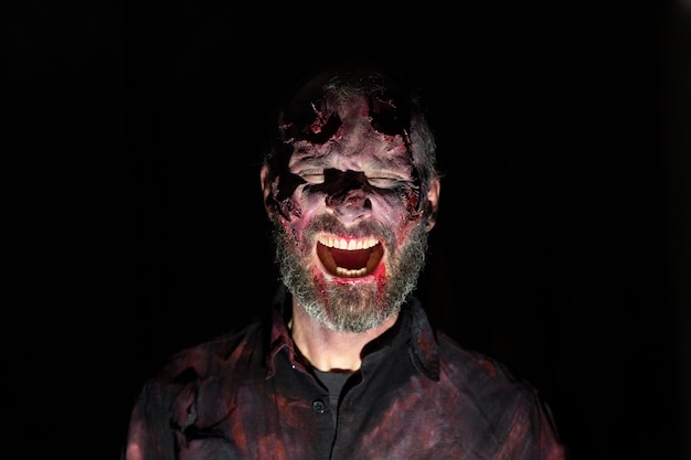 Retrato de homem zumbi no escuro com maquiagem para festa de halloween