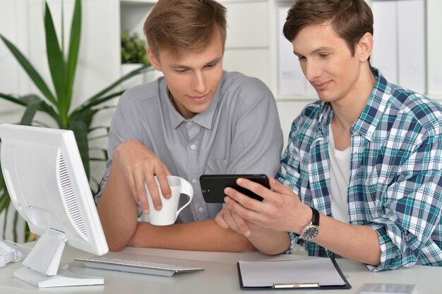 Retrato de homens bonitos com computador e telefone juntos