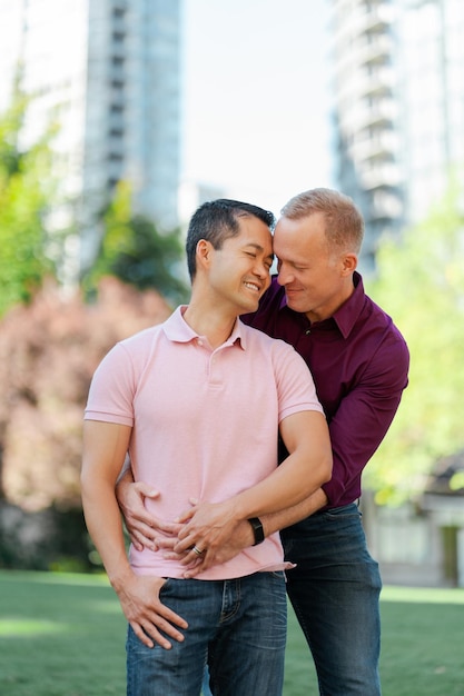 Retrato de homens gays sorridentes, apaixonados, abraçados com os olhos fechados, ao ar livre, na rua urbana