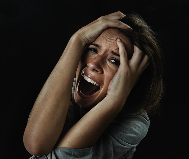 Foto retrato de horror e medo com mulher gritando em estúdio em fundo preto para reação ao perigo estresse facial e saúde mental com jovem assustado no escuro para pesadelo ou terror de fobia