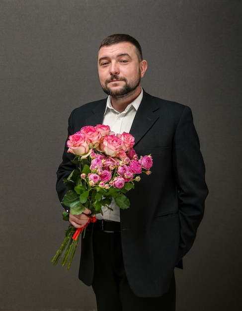 Retrato de imagem de um jovem em uma jaqueta com um buquê de rosas