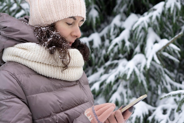 Foto retrato de inverno ao ar livre. linda mulher de 45 anos de idade falando ao celular em um parque de inverno nevado.