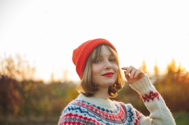 Retrato de inverno brilhante de uma bela jovem em um chapéu vermelho tricotado contra o fundo das árvores de Natal Eco natal inverno feriados ano novo