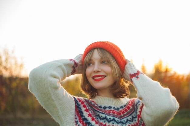 Retrato de inverno brilhante de uma bela jovem em um chapéu vermelho tricotado contra o fundo das árvores de Natal Eco natal inverno feriados ano novo