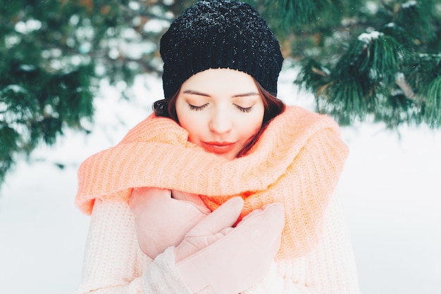 Retrato de Inverno de jovem morena vestindo blusa de malha rosa. Garota de olhos fechados.