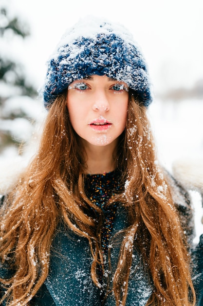 Retrato de Inverno de menina morena cabelos longos bonita com o rosto e cabelos cobertos de neve.