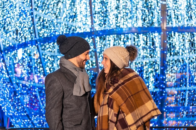 Retrato de inverno de um casal caucasiano apreciando as luzes de Natal com tochas nas mãos