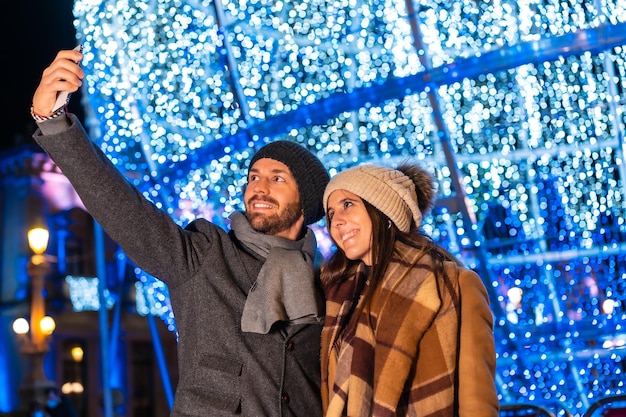 Retrato de inverno de um casal caucasiano apreciando as luzes de Natal com tochas nas mãos