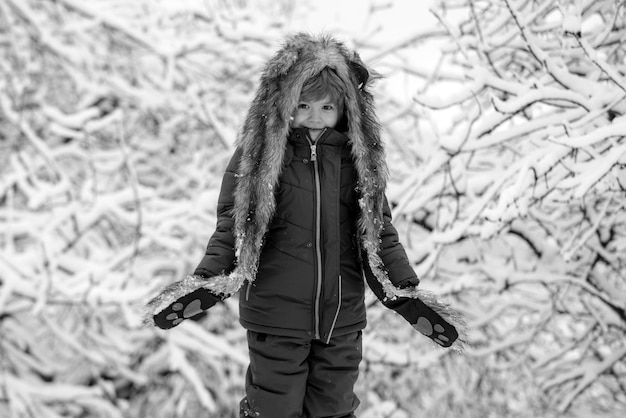 Retrato de inverno de uma criança fofa no jardim de neve feliz inverno menino sonha com inverno