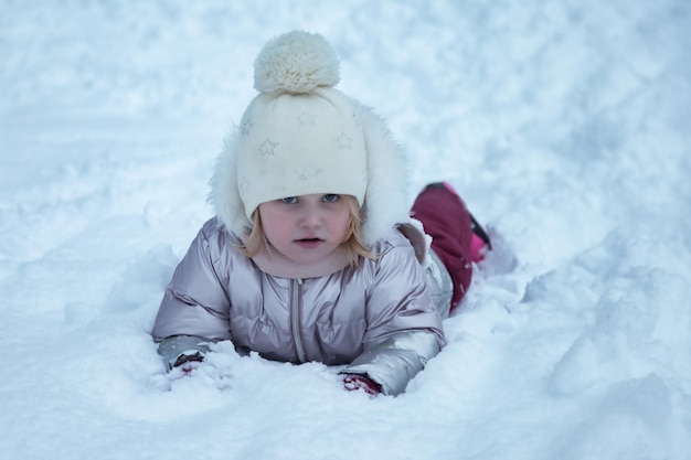 Retrato de inverno menina feliz no parque público nevado em roupas quentes