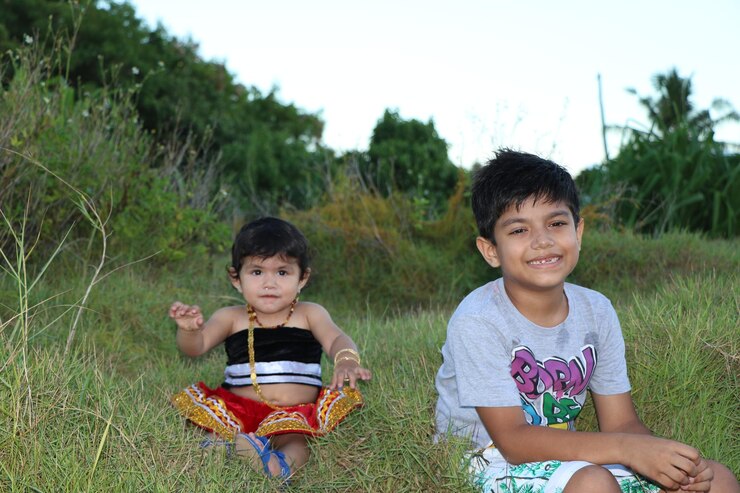 Foto retrato de irmãos bonitos sentados na grama contra o céu