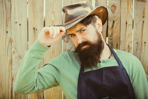 Foto retrato de jardineiro barbudo em fundo de madeira, um homem bonito passa o tempo na agricultura do trabalhador agrícola