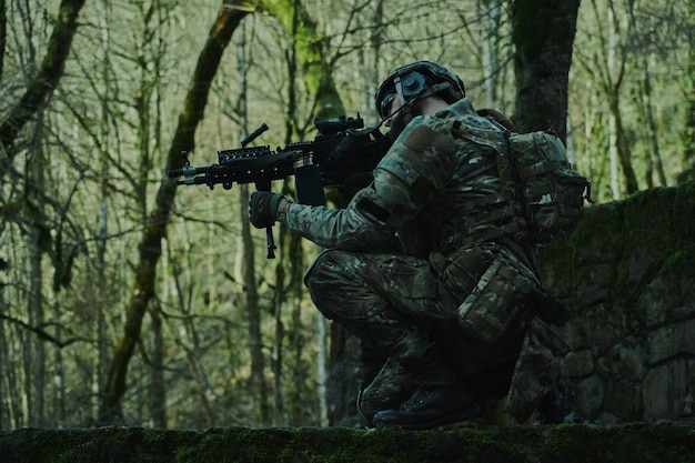 Retrato de jogador de airsoft em equipamento profissional com metralhadora na floresta. Soldado com armas em guerra