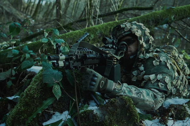 Retrato de jogador de airsoft em equipamento profissional em capacete visando a vítima com arma na floresta. Soldado com armas em guerra