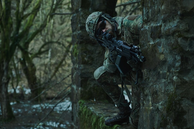 Retrato de jogador de airsoft em equipamento profissional em capacete, visando a vítima com arma na floresta. soldado com armas em guerra