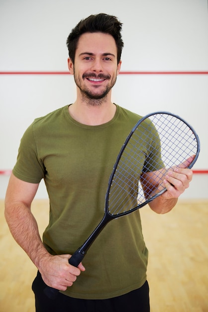 Retrato de jogador de squash com raquete na quadra