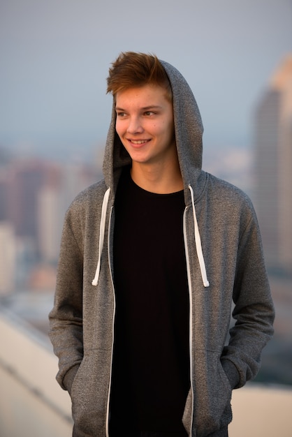 Retrato de jovem adolescente bonito contra a vista da cidade ao ar livre