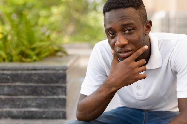 Retrato de jovem africano em edifício moderno ao ar livre da cidade