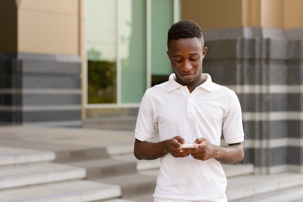 Retrato de jovem africano em edifício moderno ao ar livre da cidade