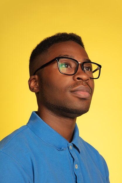 Retrato de jovem afro-americano isolado no fundo amarelo do estúdio, expressão facial.