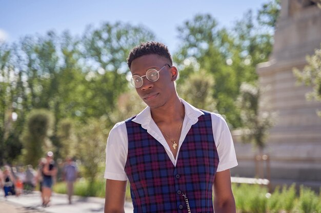 Retrato de jovem afro-americano vestindo colete e camisa com óculos na rua