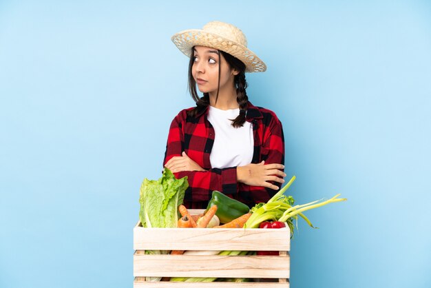 Retrato de jovem agricultor segurando legumes frescos em uma cesta de madeira